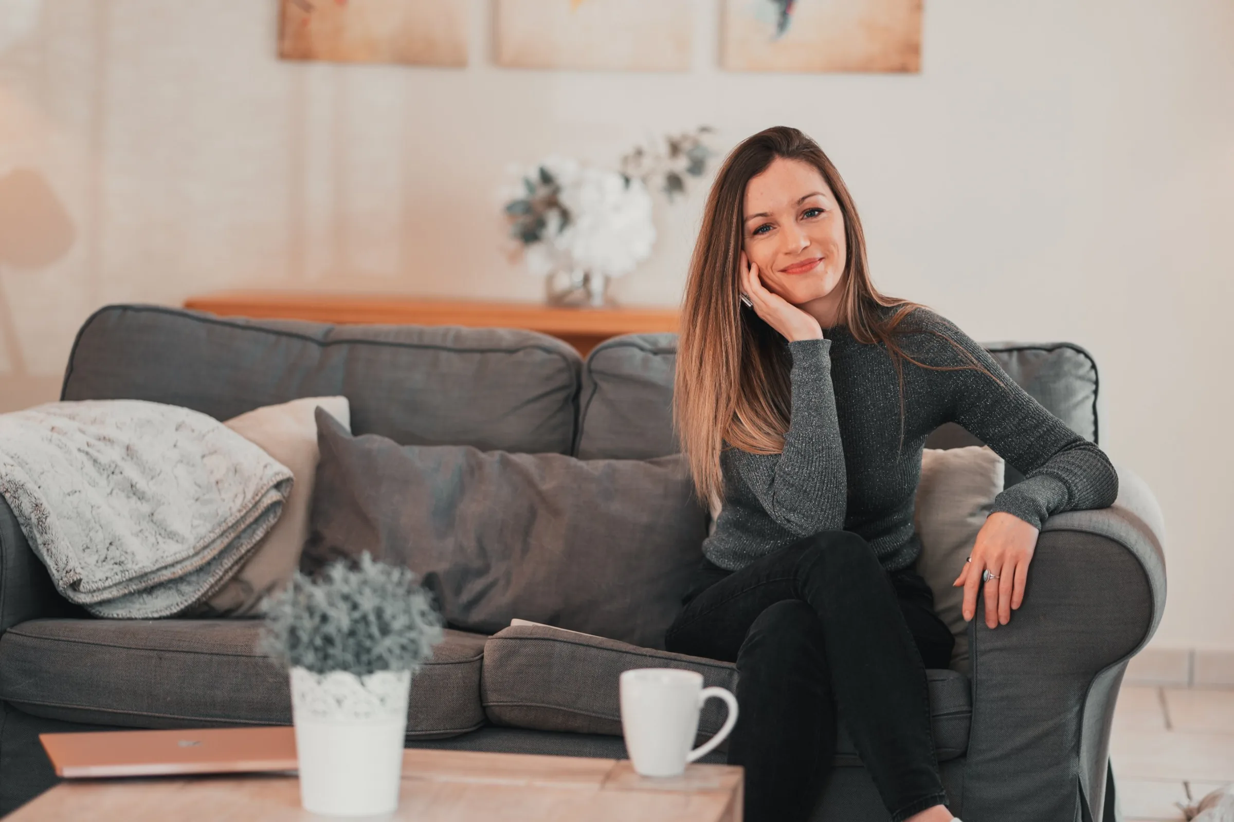 Amandine souriante, assise dans un canapé